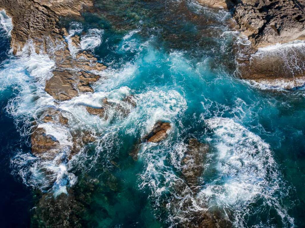 waves crashing on rocky shoreline of comino island