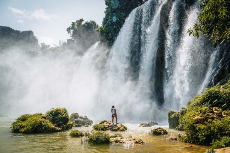 Nomadicated silhouette standing underneath the smaller vietnamese side only ban gioc waterfall