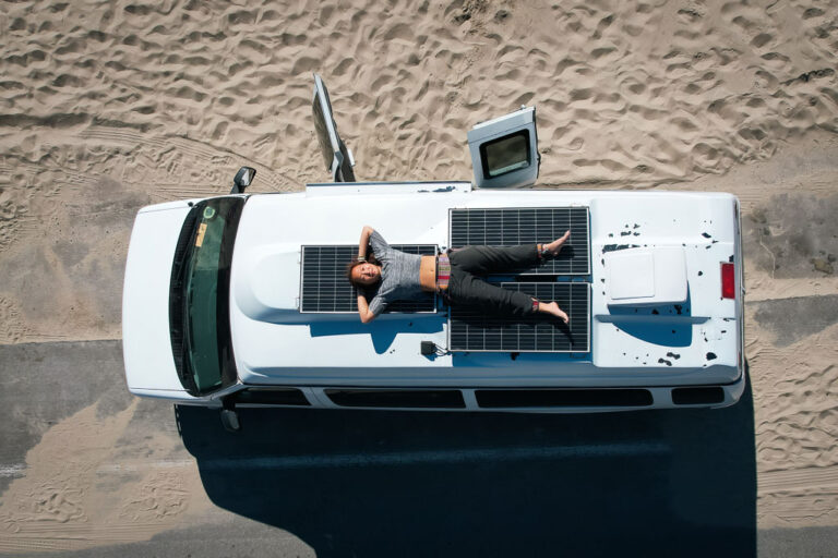 Nomadicated lying on a camper van on a California beach