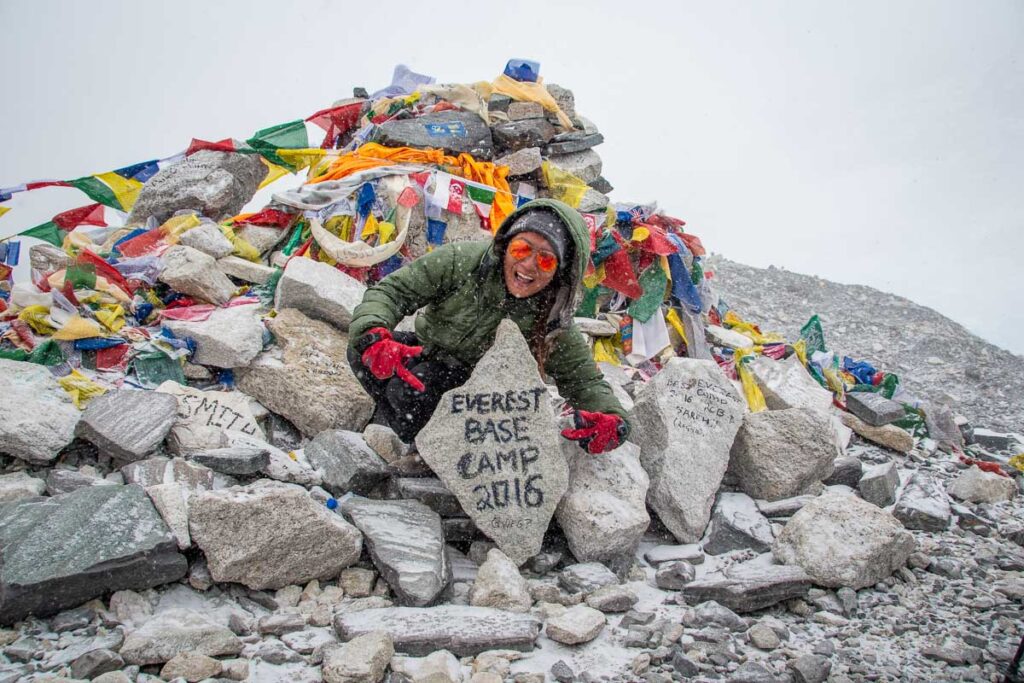 nomadicated proudly holding the everest base camp sign