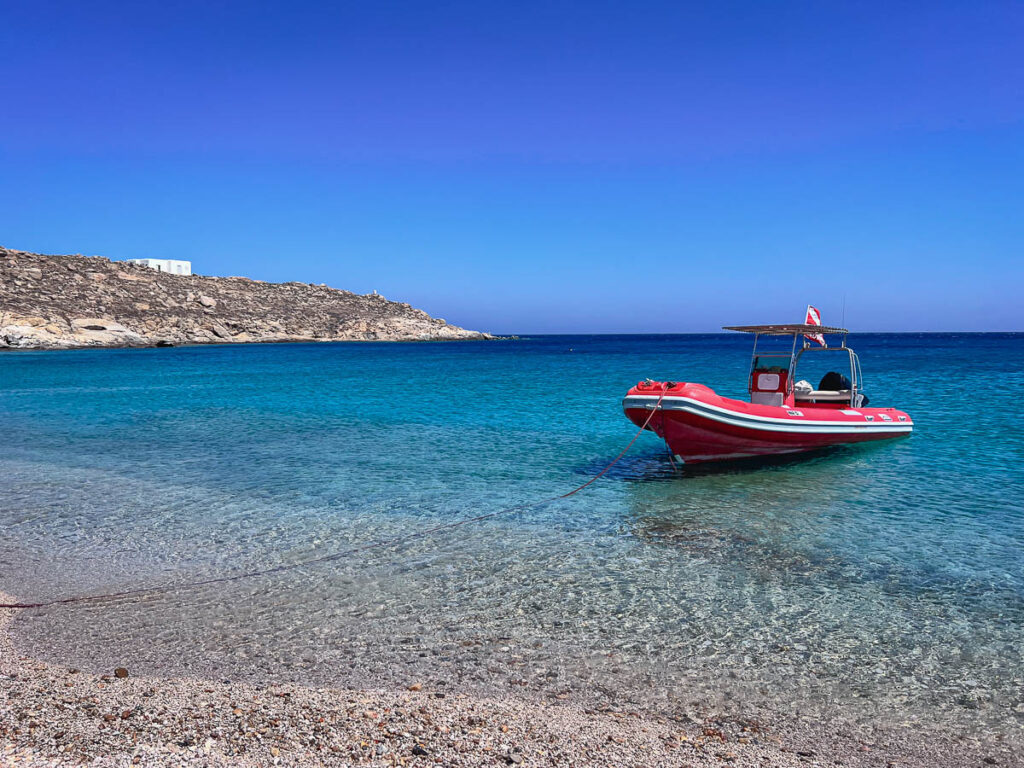 boat floating in the clear blue water beaches of Mykonos