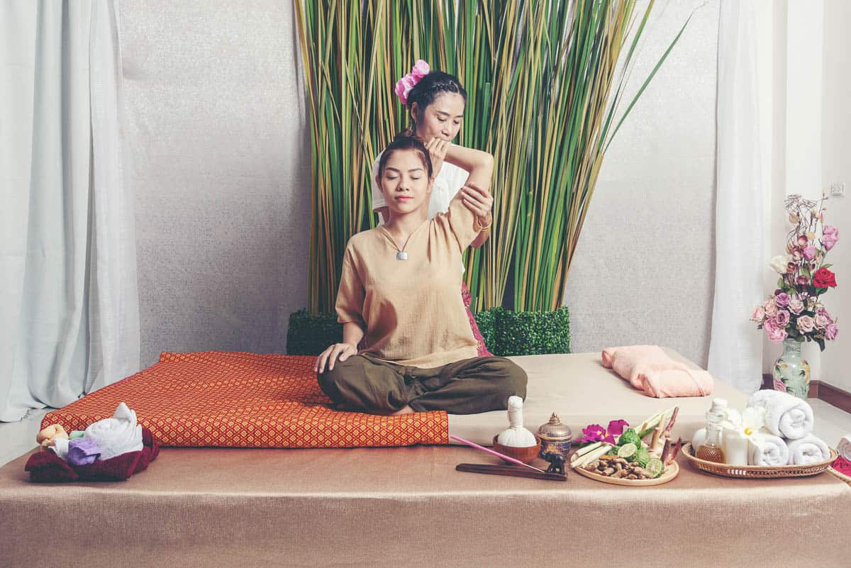 Thai Masseuse doing massage for lifestyle woman in spa salon. Asian beautiful woman getting Thai herbal massage compress massage in spa.She is very relaxed. Healthy Concept.