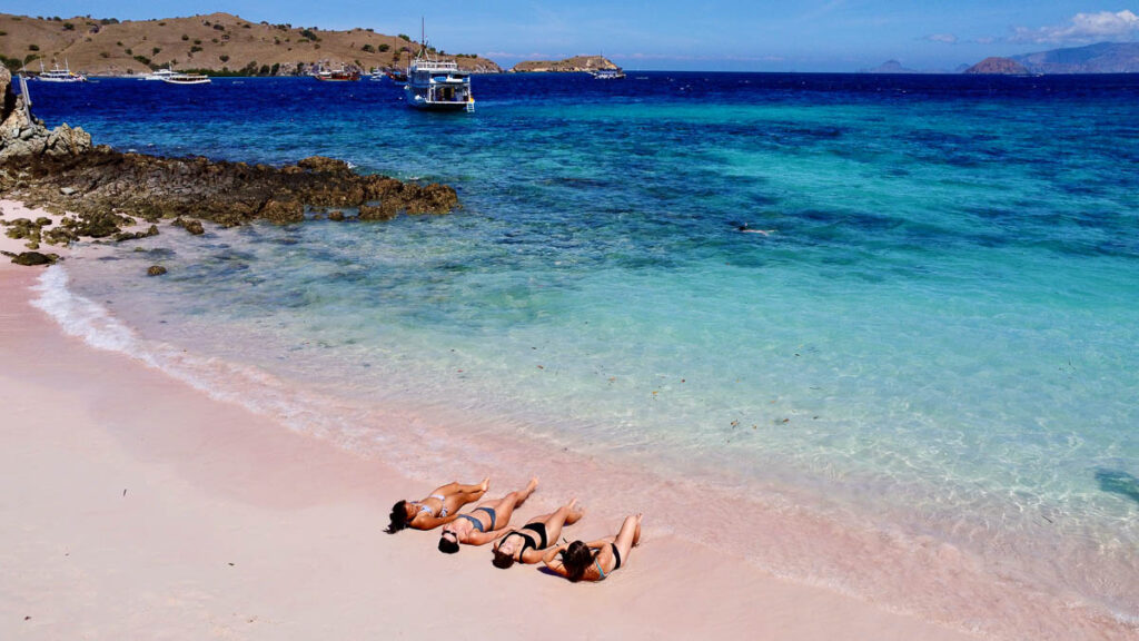 four girls lounging on pink beach in komodo national park