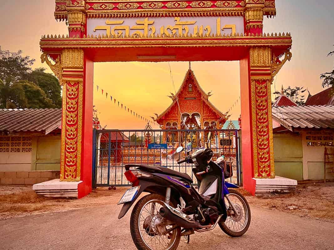 Scooter in Thailand in front of a sunset temple