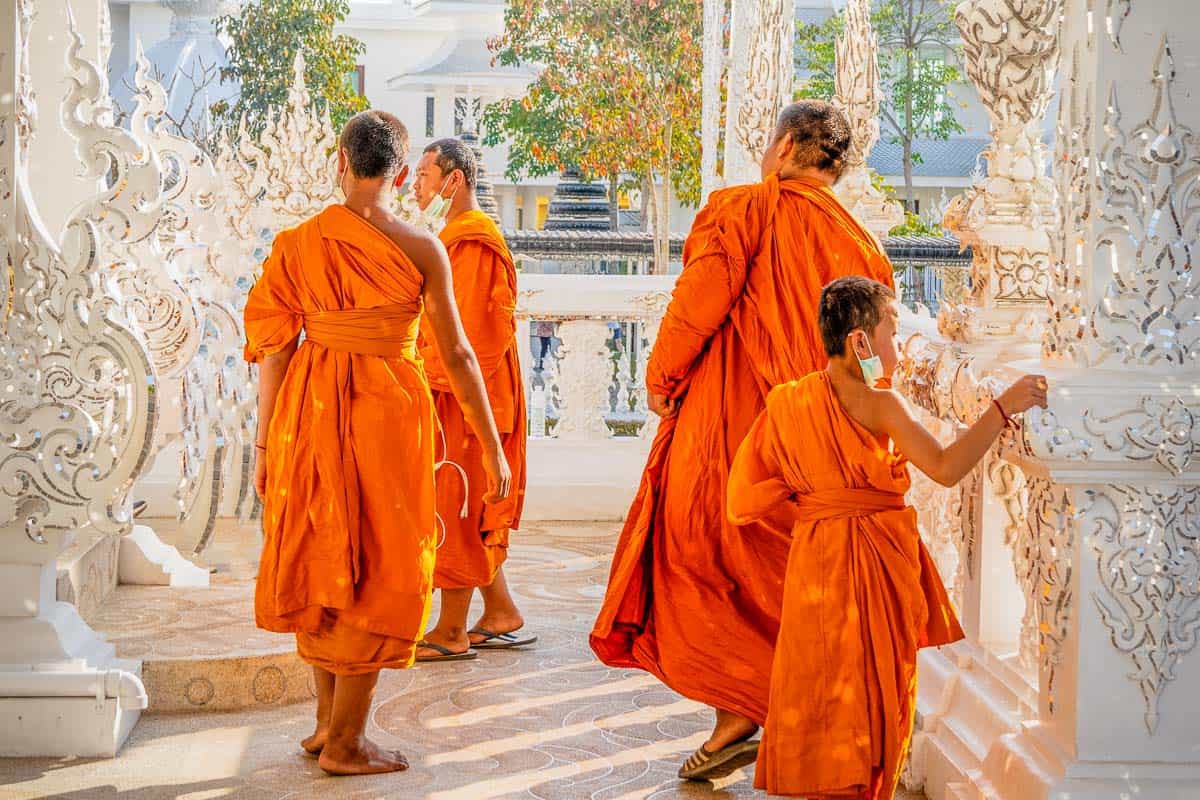 group of monks in golden hour at white temple chiang rai